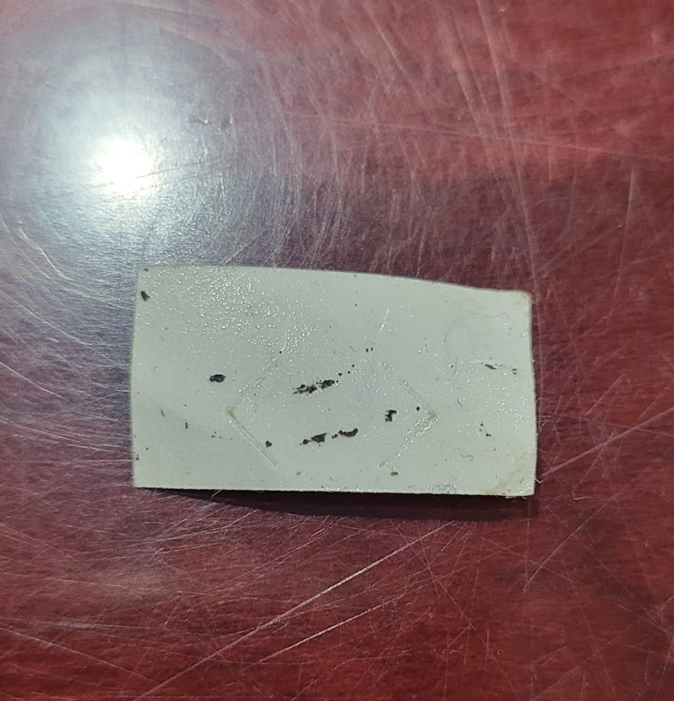 This is the back of the sticker that was on the front of the case. Notice that it pulled up some of the layers of the case material. These adhesives are not designed for artifacts--they are designed to put price tags on merchandise--and they do cause damage when used in this way.
