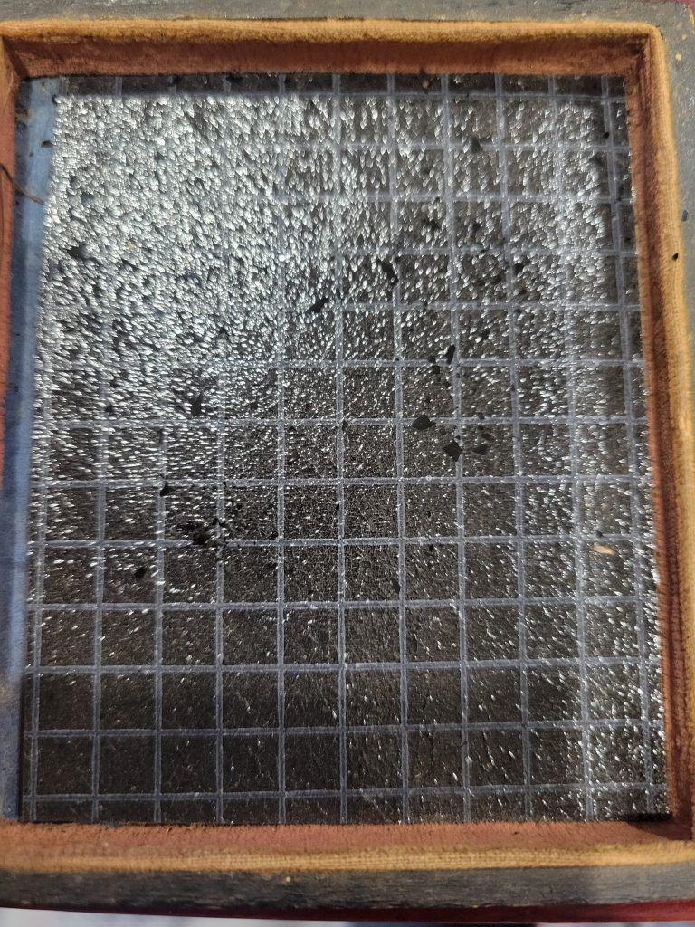 The paper in question. Here is a photo of the black sandpaper like material cut to fit inside the case. Notice the specks of black material laying on top of it. Those are pieces of the ambrotype's original varnish that have flaked off onto the sandpaper.